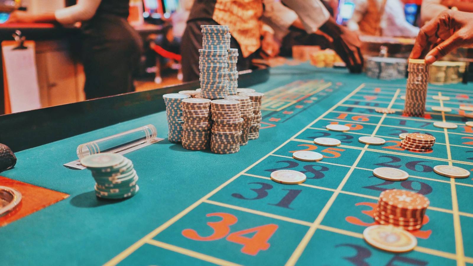 Meja kasino dengan tumpukan chip poker di bawah pencahayaan hangat